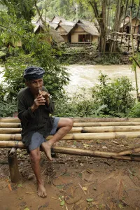 Pria Baduy berikat kepala duduk di bangku bambu dekat sungai