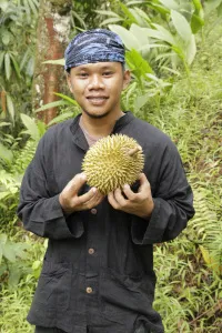 Pemuda Baduy berikat kepala memegang durian