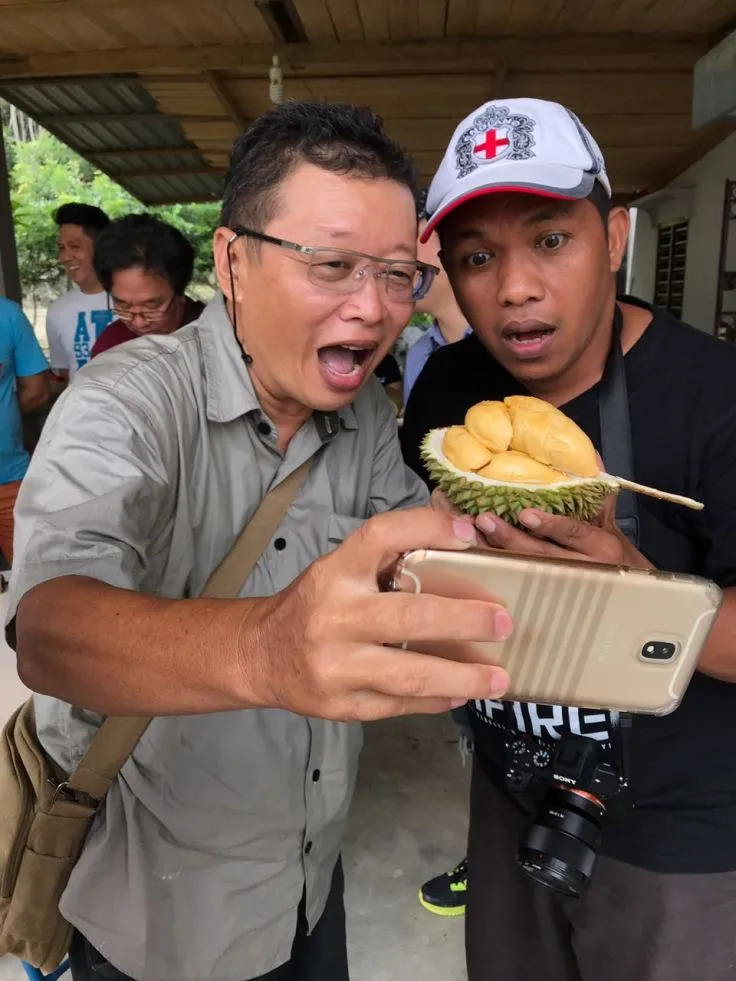 Dua peserta tur memotret durian berdaging kuning dengan ponsel