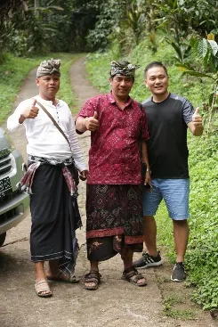Tiga pria mengacungkan jempol di jalan desa