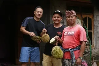 Tiga pria berpose memegang durian
